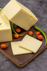 Cheddar cheese or kashkaval cheese on dark background. Cheese slices on the serving board