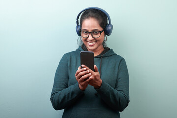 Portrait of a woman of Indian ethnicity with a happy surprised face looking at her mobile phone