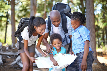 Which way should we go next. A happy african family looking at a map while taking a hike together.