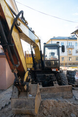 The excavator is working on the construction site to replace the pipeline in winter. Digging holes for laying new pipes for central heating in a residential area.
