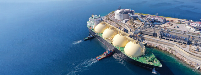 Aerial drone ultra wide panoramic photo with copy space of LNG (Liquified Natural Gas) tanker anchored in small gas terminal island with tanks for storage - obrazy, fototapety, plakaty