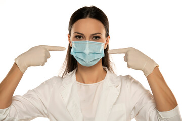 Beautiful female doctor or nurse wearing protective mask and latex or rubber gloves on white background .