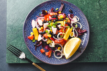 Plate of delicious Mexican vegetable salad with black beans and radish on table, closeup