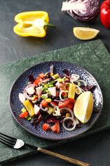 Plate of tasty Mexican vegetable salad with black beans and radish on dark background
