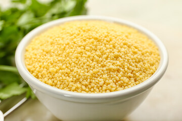 Bowl of raw couscous on table, closeup