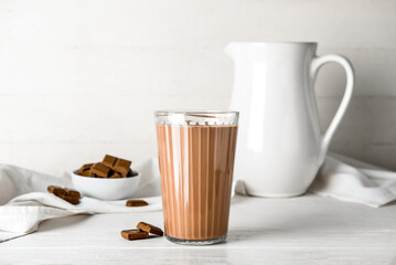 Glass of delicious chocolate milk on table