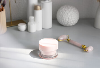 Jar of cosmetic product and facial massage tool on table
