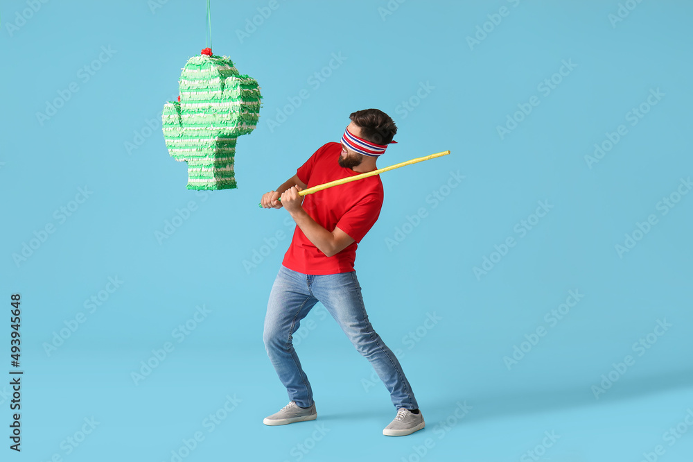 Sticker Handsome man breaking Mexican pinata on color background