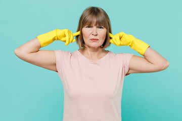 Elderly housewife woman 50s in pink t-shirt gloves cover ears with hands fingers do not want to...