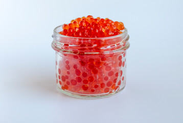 Red caviar in a glass jar on a white background