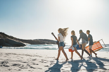 Fototapeta premium Happiness is a day spent at the beach. Shot of a group of young friends walking on the beach on a sunny day.