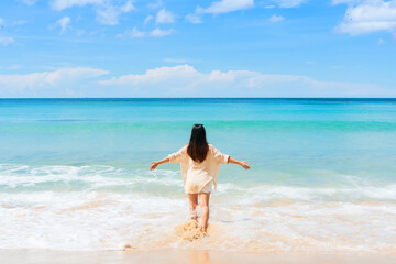 Rear view of happy traveler Asian woman enjoys at tropical beach on vacation. Summer on beach, travel and vacation concept. Copy space