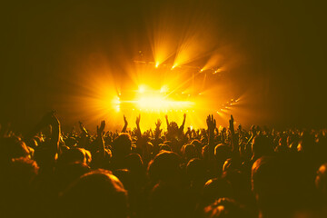 A crowded concert hall with scene stage orange and yellow lights, rock show performance, with...