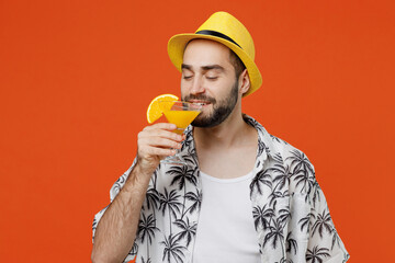 Young tourist man wear beach shirt hat travel abroad on weekends hold sniff alcohol cocktail close...