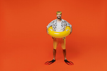 Full body smiling young tourist man in beach shirt goggles hold inflatable ring flippers travel abroad on weekends isolated on plain orange background studio Summer vacation sea rest sun tan concept. © ViDi Studio