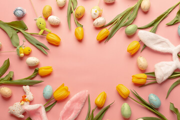 Yellow tulips and easter decor on a pink background. Copy space centered. Top view