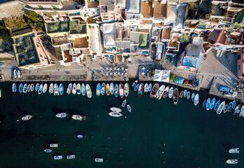 Fototapeta na wymiar Colored boats anchored at small seaside town quay (aerial drone photo). Mediterranean, Procida, Italy