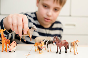 Kid plays with plastic figurines of animals. Protection of animals. PETA. Children's toys giraffe,...