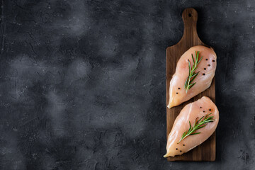 raw fresh chicken fillet with rosemary and spices on a dark background