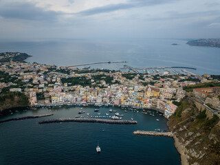 Fototapeta na wymiar Colored boats anchored at small seaside town quay (aerial drone photo). Mediterranean, Procida, Italy