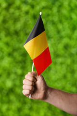 Male hand with Belgian flag on color background