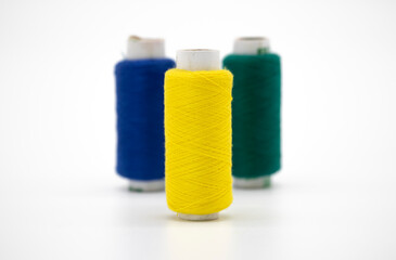 Sewing thread and bobbin in yellow color on isolated white background