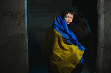 Sad mother hugging her son, both wearing Ukrainian national colors on black background.