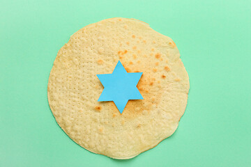 Jewish flatbread matza for Passover with paper David star on green background
