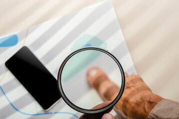 Male detective hand holding magnifying glass while searching information