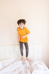 Naklejka premium An energetic child is jumping on the bed