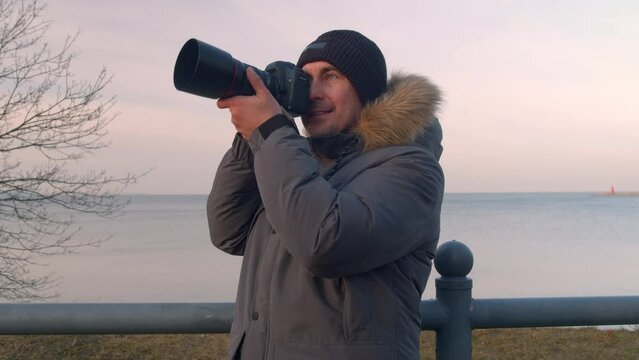 Professional male photographer takes pictures of the seascape with a SLR camera takes pictures of the picturesque landscape nature travel adventures.