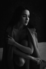 Black and white portrait of attractive young woman in lingerie and coat