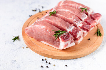 A pieces of raw fresh pork with rosemary on a cutting board on light background. Meat with spices