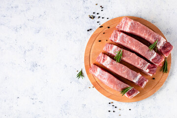 A pieces of raw fresh pork with rosemary on a cutting board on light background. Meat with spices