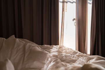 bed with white wrinkle blanket mattress pillow in unmade bed with morning sunlight through big...