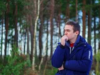 person looking away. The guy stands in the background of the forest