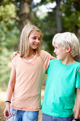 Cute siblings. Young siblings standing outdoors with arms around.