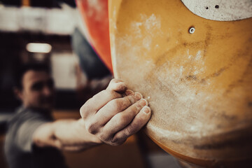 Male hand smeared with magnesium powder grabbing a hold of a climbing wall