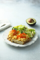 Scrambled eggs with red caviar on toast