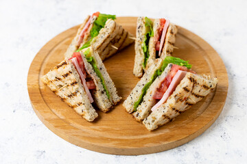 sandwich with ham cheese tomatoes lettuce onions on cutting board. Classic club sandwich with whole grain bread