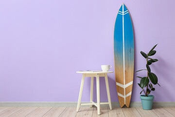 Interior of room with surfboard, houseplant and table near color wall