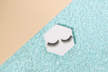 Modern minimal summer makeup concept with black fake eyelashes on blue beach water. Trendy beauty...
