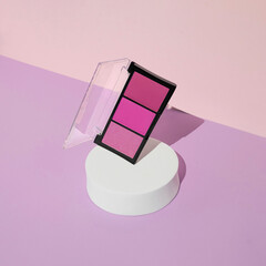Minimal trendy beauty concept with pink eye shadow palette  on pastel purple background. Trendy summer make-up composition.