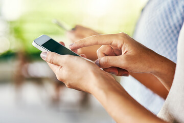 Im getting messages non stop. Shot of an unrecognizable woman browsing on her cellphone while standing inside of a cafe during the day.