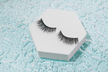 Modern minimal summer makeup concept with black fake eyelashes on blue pool water. Trendy beauty...