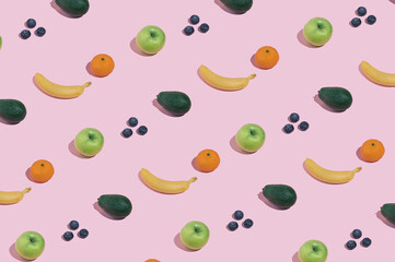 Modern minimal pattern with fruit, bananas, blueberries, apples, avocado and oranges on bright pink background. Trendy female healthy eating aesthetic.