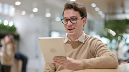 Portrait of Young Man doing Video Chat Tablet in Office 