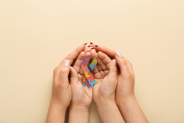 Mother with her child and awareness ribbon on beige background. Concept of autistic disorder