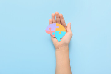 Child with paper brain on blue background. Concept of autistic disorder