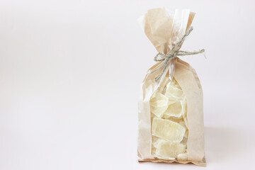 Superfood dried (dehydrated) Aloe Vera chunks in the brown beige craft packaging bag , isolated on white, light pink background, copy space on the left, retail, horizontal plane